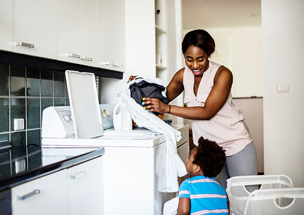 A woman and child in the kitchen doing laundry.