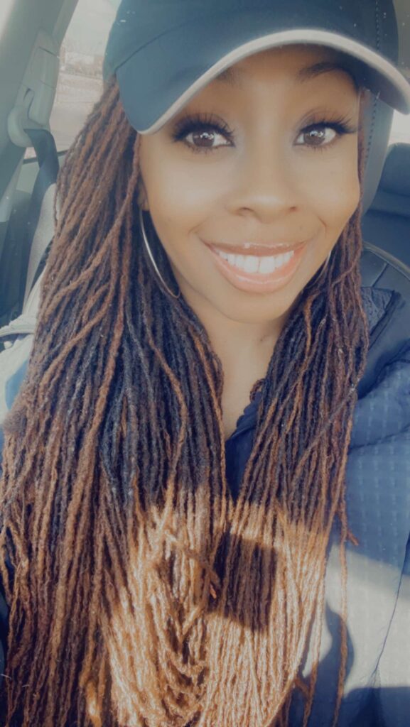 A woman with long dreadlocks smiling for the camera.