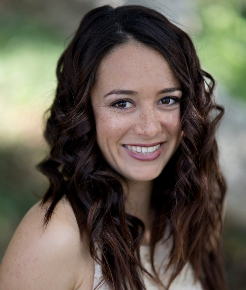 A woman with long brown hair smiling for the camera.