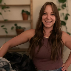 A woman standing in front of some clothes.